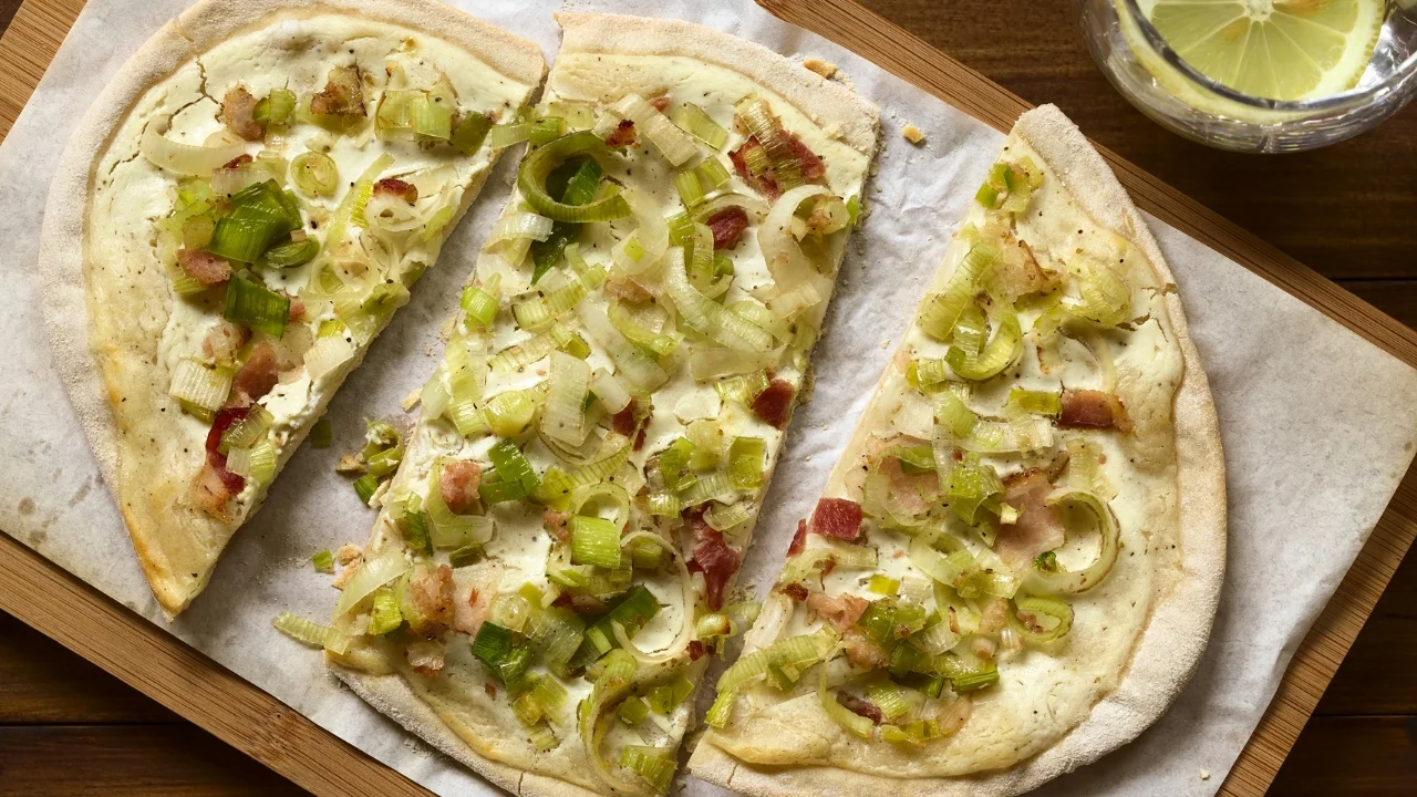 TArta z porem na cieście francuskiem na drewnianej desce przykrytej papierem do pieczenia